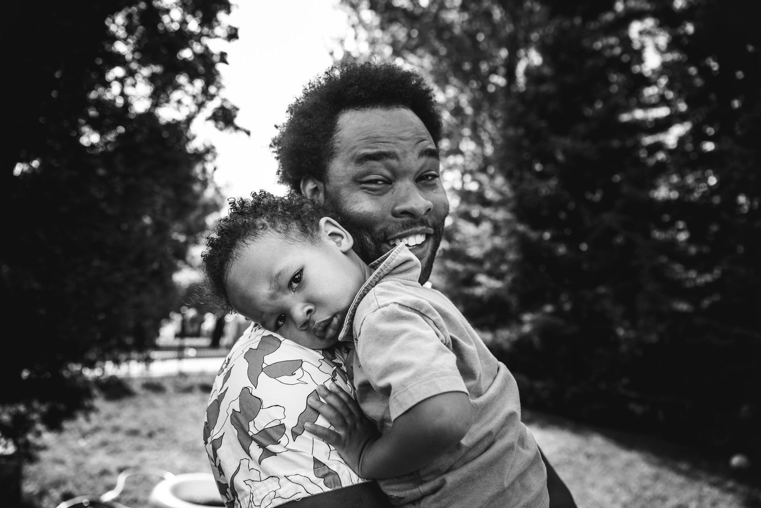 A man holds his son, both looking at the camera.