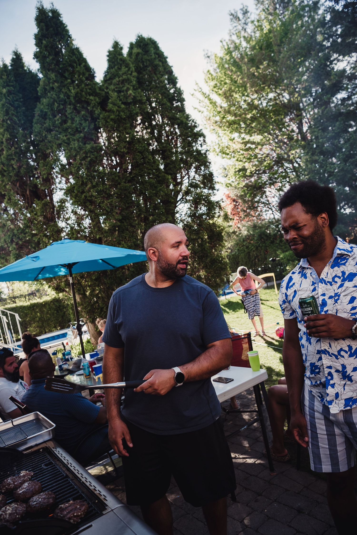 Two men talk as one man bbq.