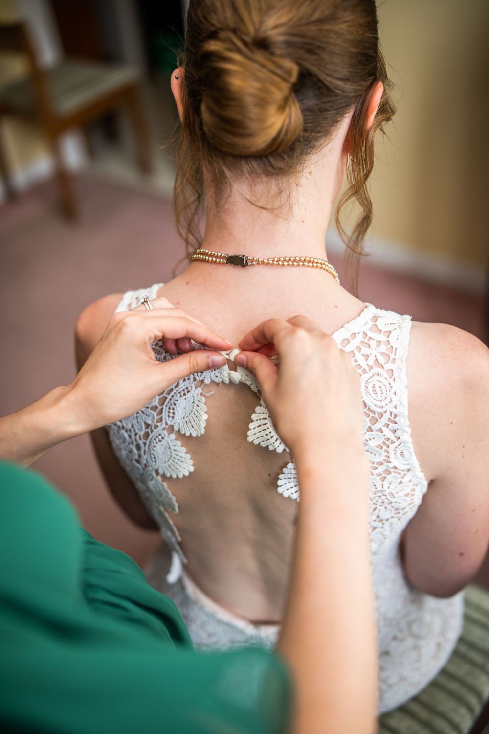 maid of honour doing up wedding dress for bride before wedding ceremony