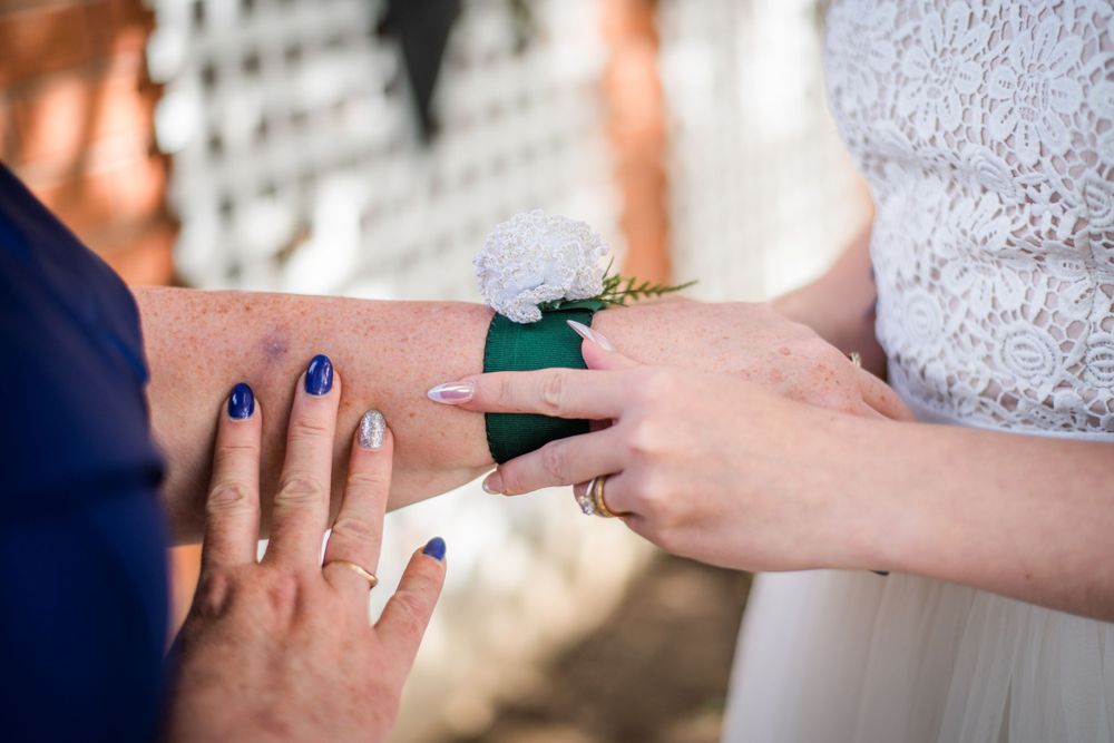 bride putting corsage on mother of the bride before wedding ceremony