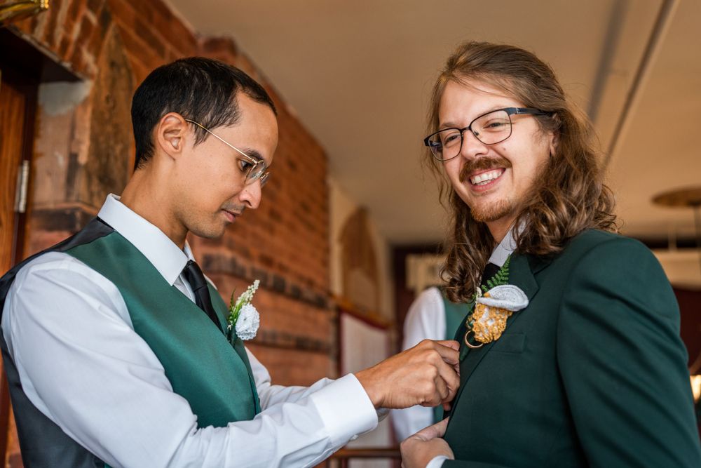 best man pinning boutonniere on groom before wedding ceremony