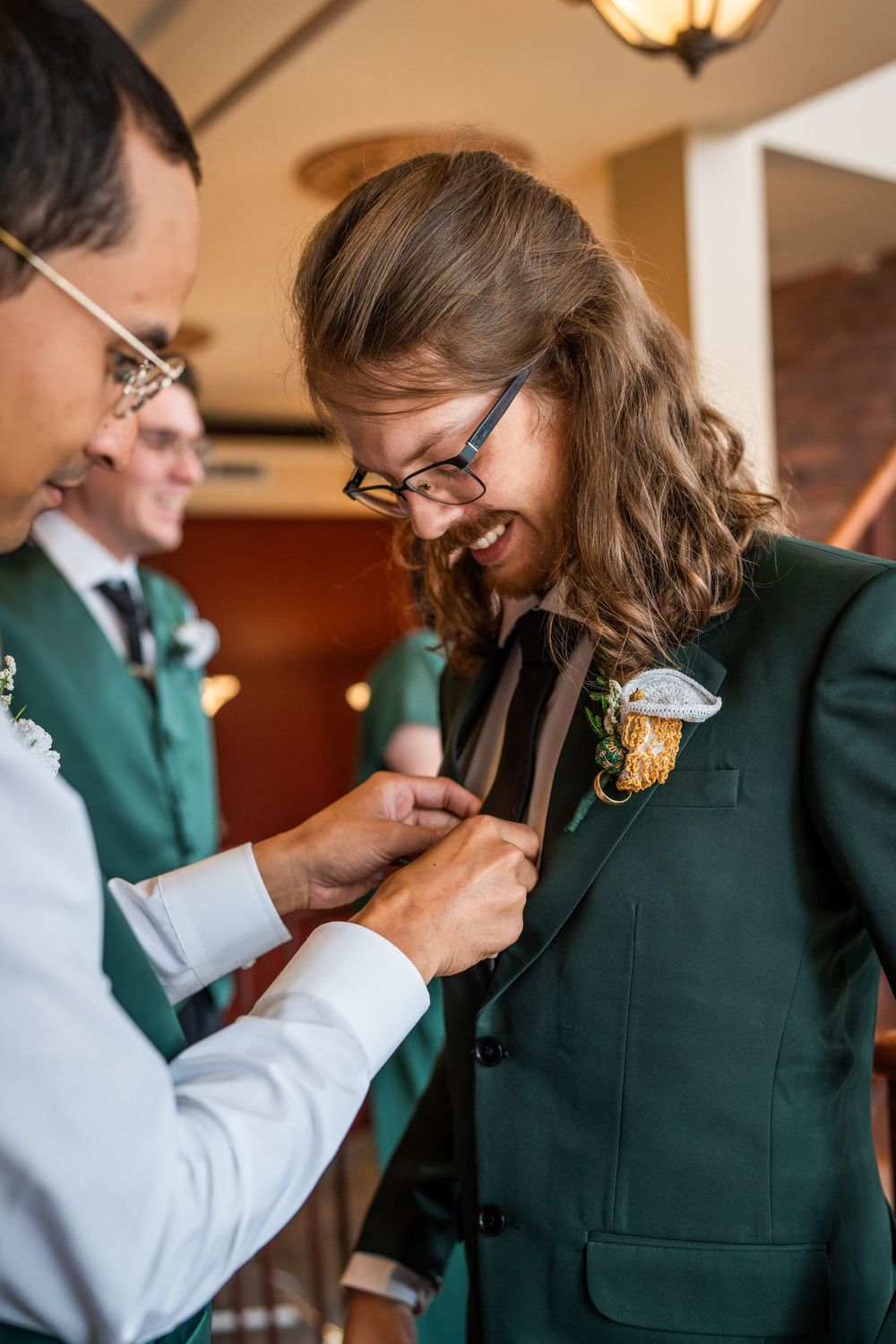 groomsman pinning boutonniere on groom before wedding ceremony