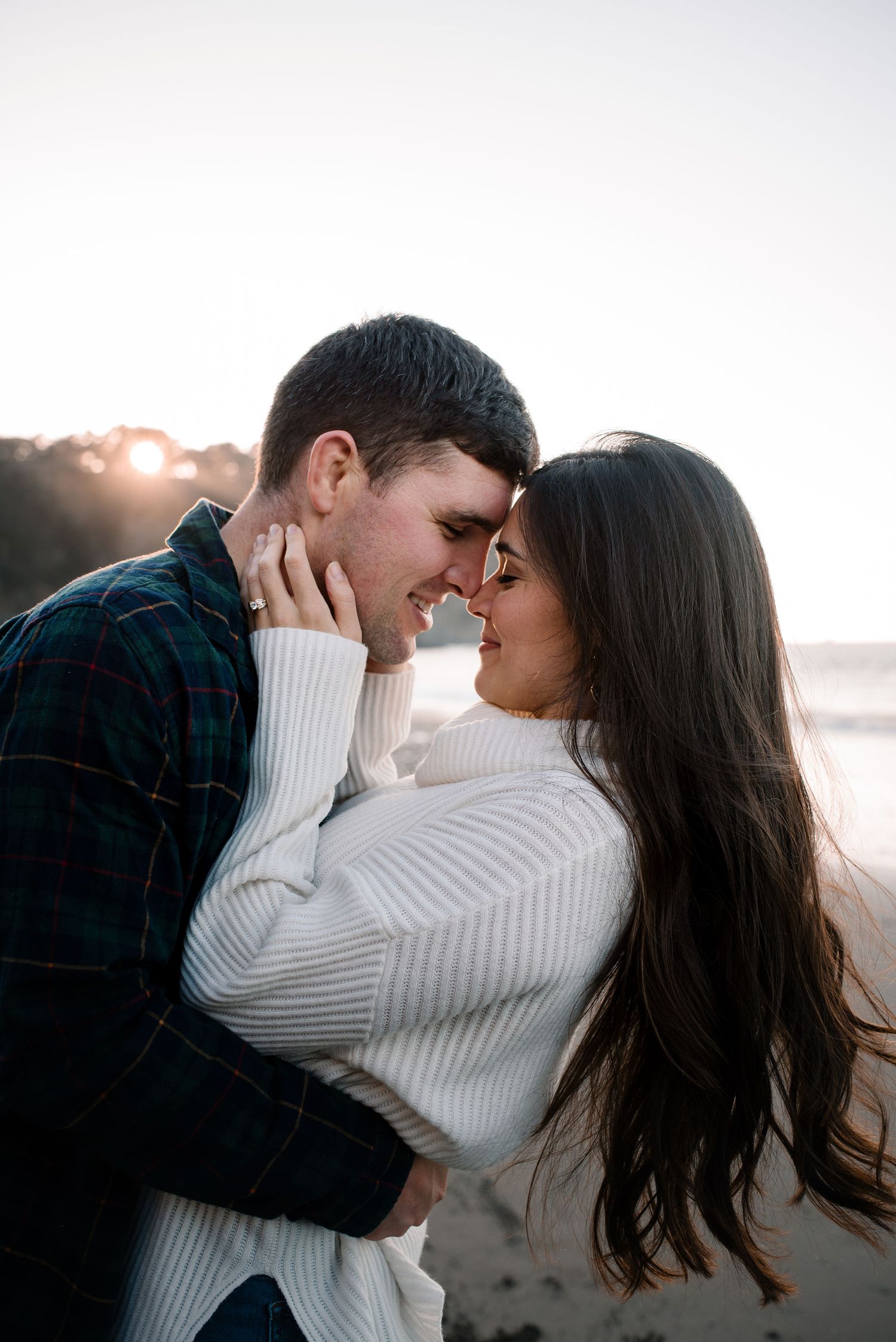 A romantic couple embraces while sharing a tender moment on the beach.