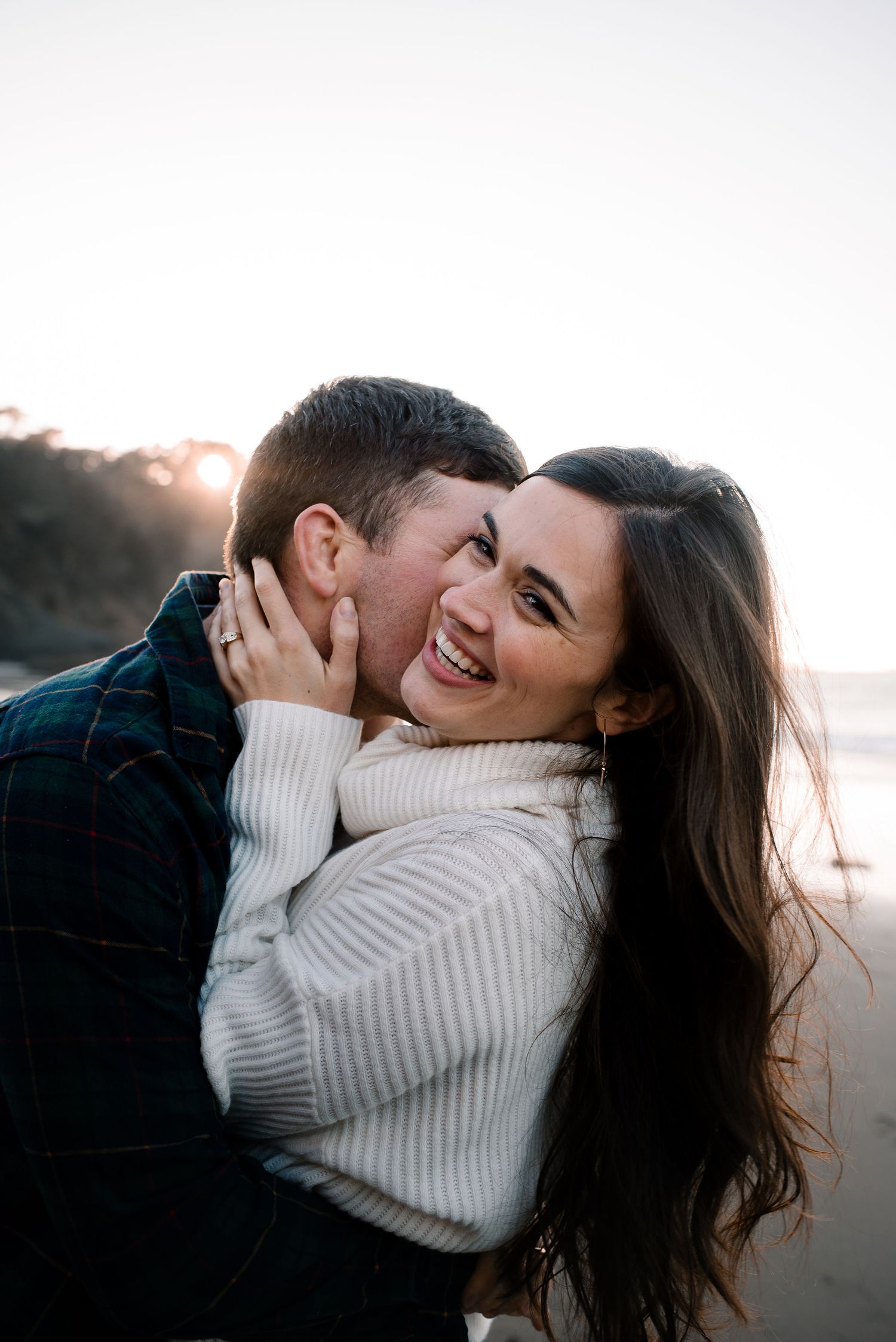 A couple shares an intimate moment on the beach during sunset.