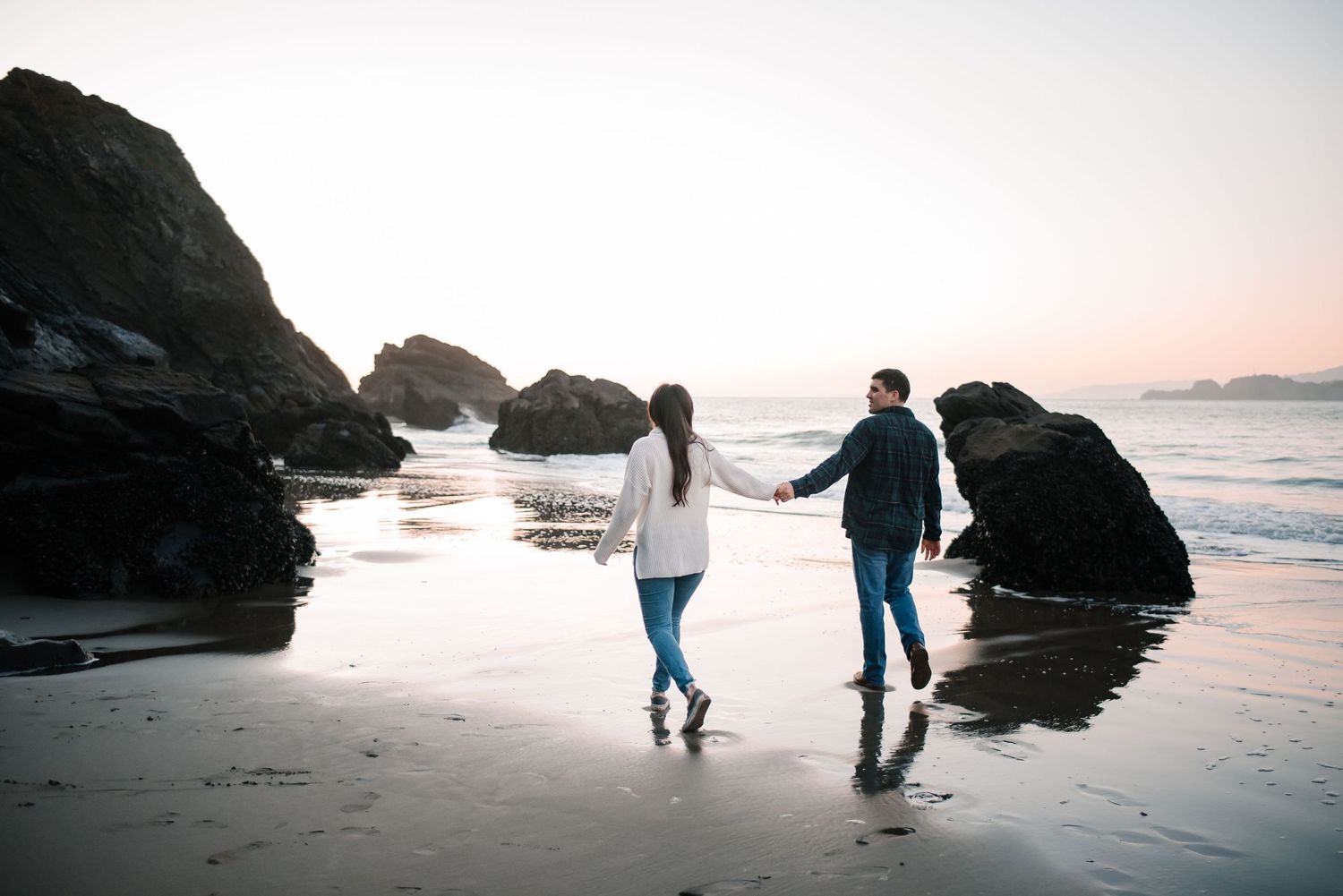 Silhouettes of people walking and playing on a beach at dusk.