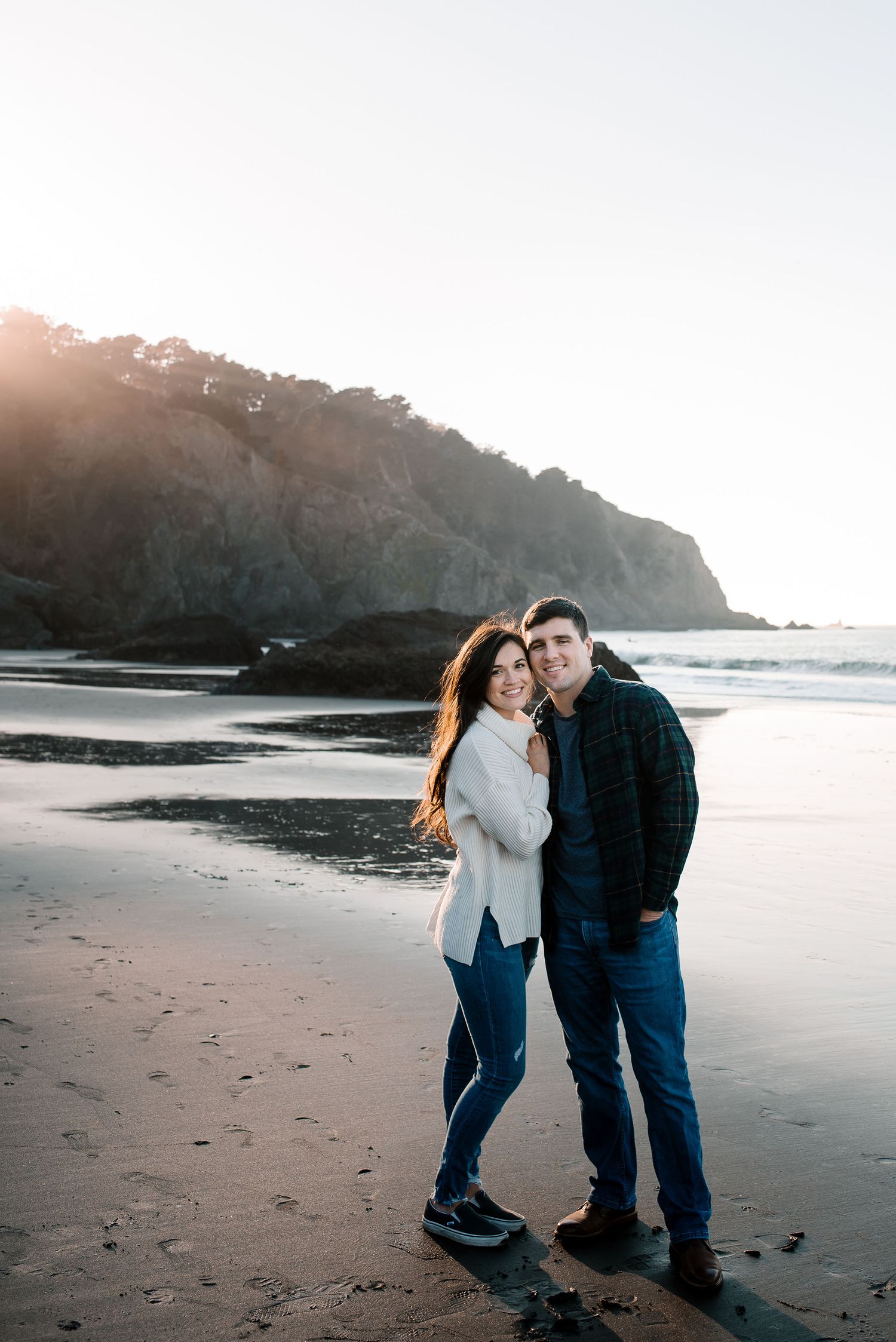A couple shares a romantic moment on a scenic beach at sunset.