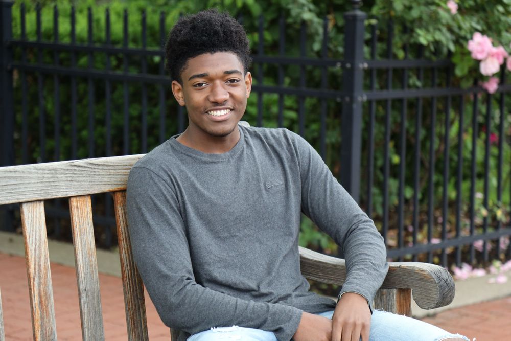 Senior boy confidently smiling as he sits on a bench