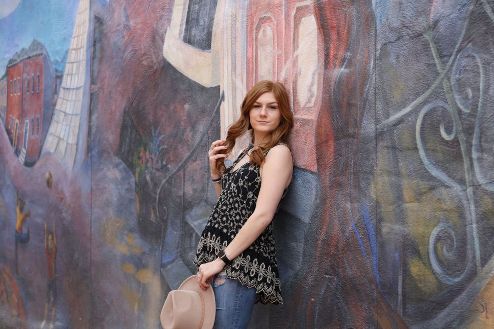 Senior girl posing with hat against a colorful mural