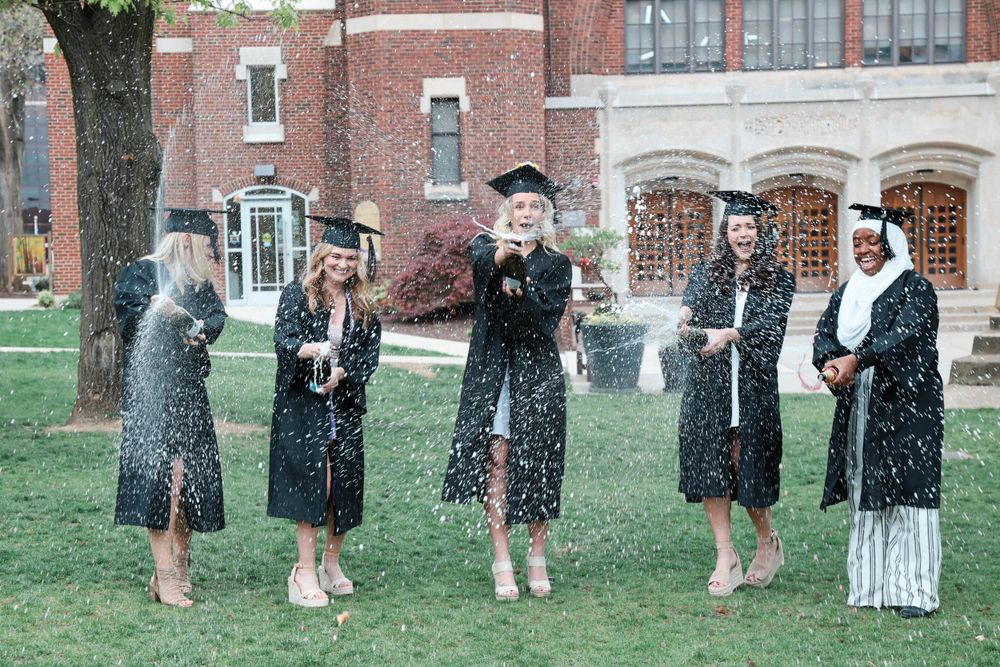 Group of college graduates popping champagne in celebration
