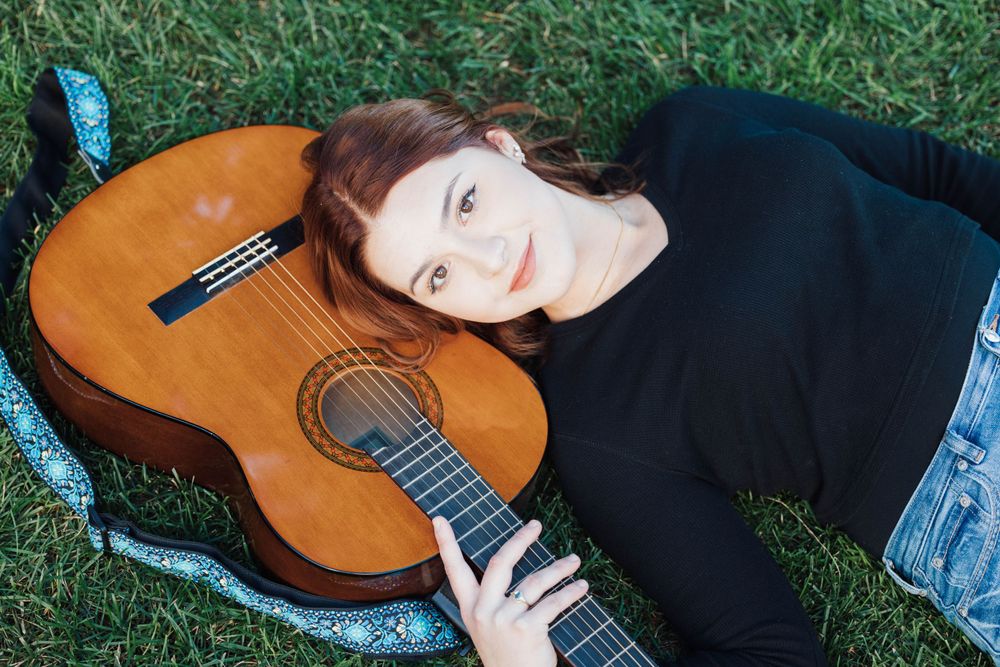 A high school senior posing with her guitar
