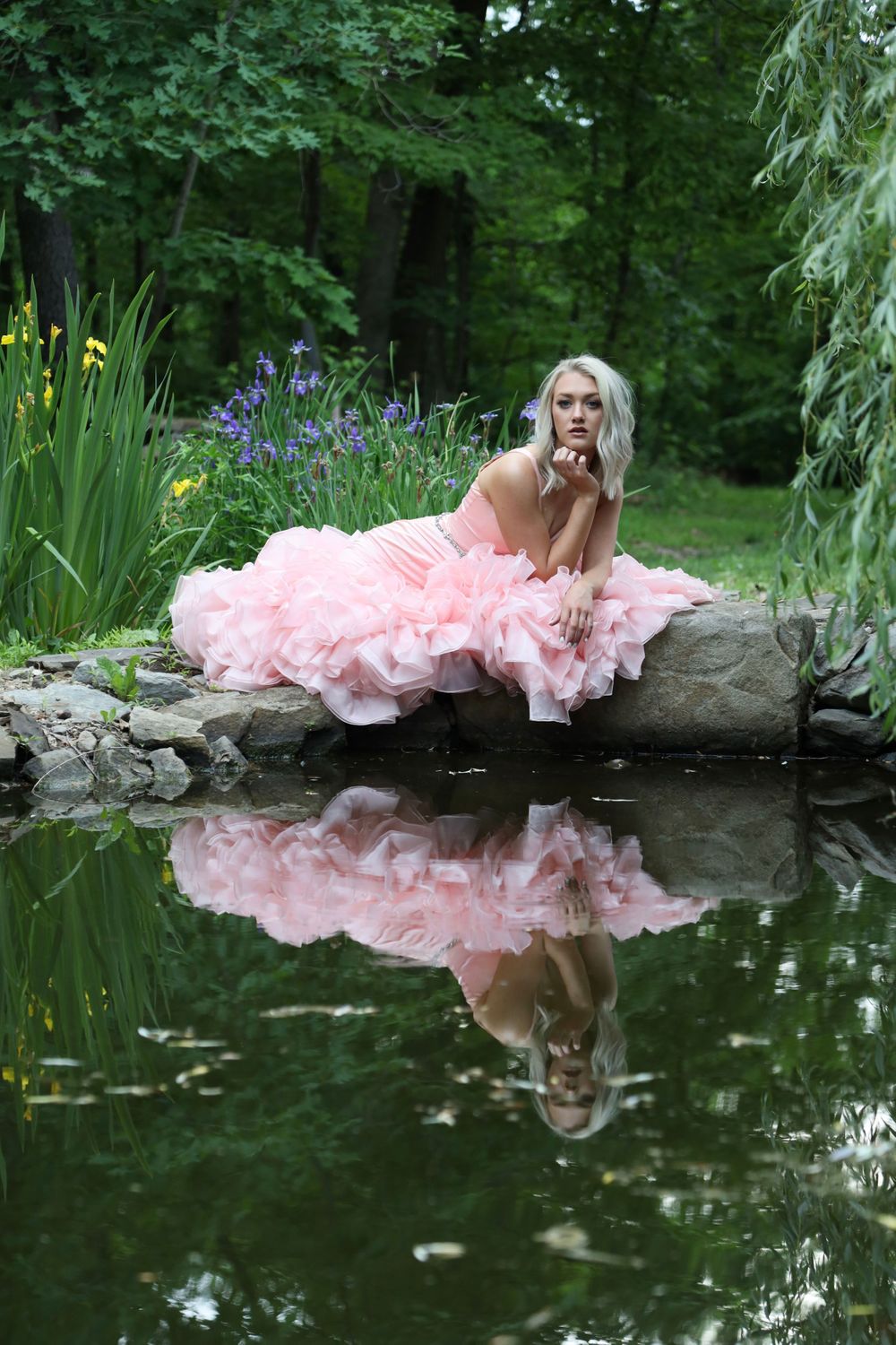 Senior girl in gown posing at a pond with her reflection
