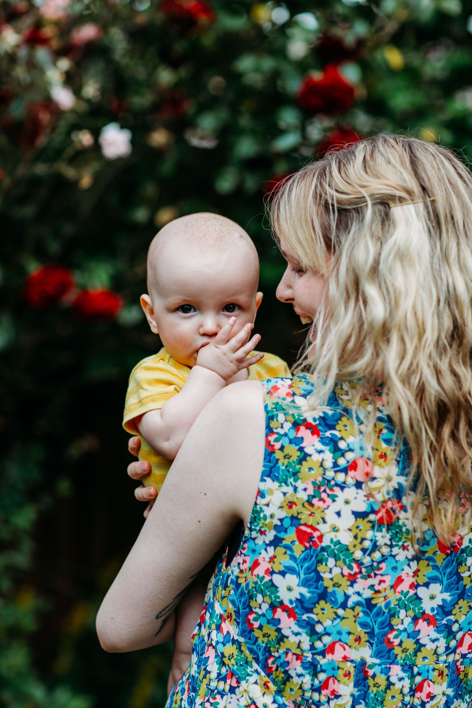 Candid outdoor portrait against a backdrop of blooming roses and greenery.