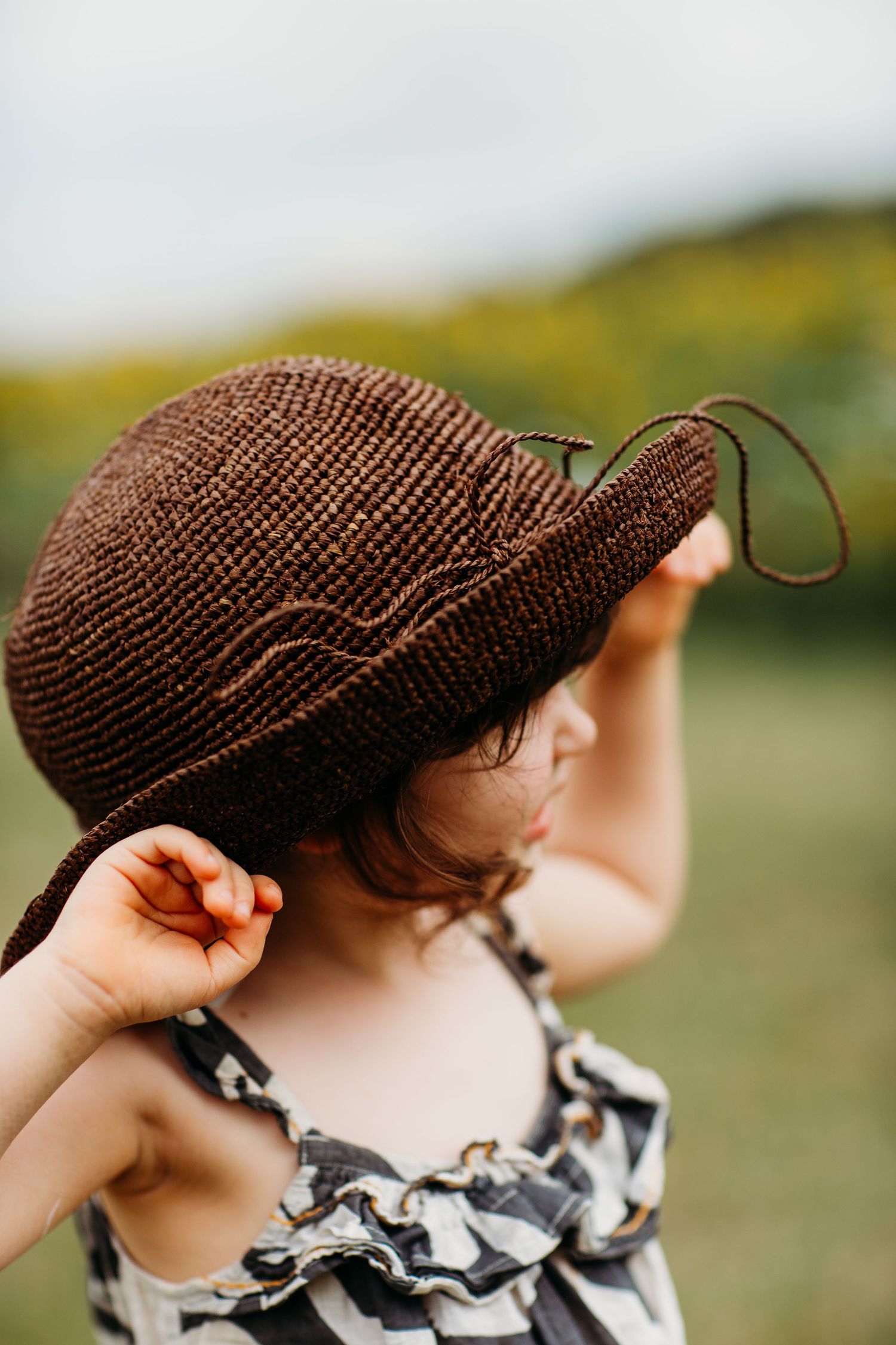 Close-up of brown woven sun hat worn on sunny summer day.