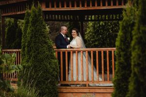 A wooden deck railing with green foliage in the background.