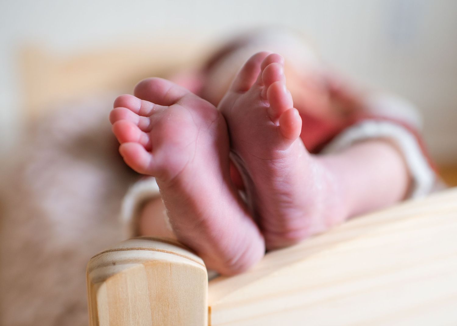 Close-up of tiny newborn baby feet against soft beige background.