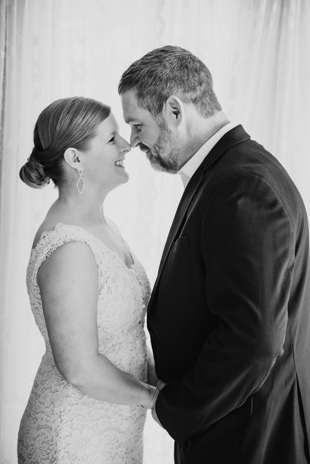 Black and white wedding portraits showing tender moments between newlyweds against white backdrop.
