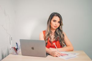 Professional working at desk with MacBook laptop and business documents.