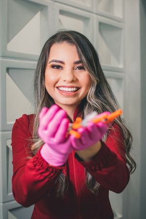 Joyful portrait showing bright smile while holding medical supplies with pink gloves.