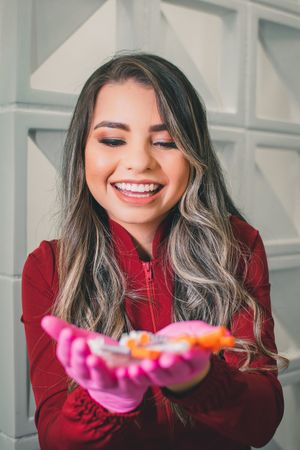 Cheerful expression while displaying medical supplies wearing protective pink gloves and red coat.