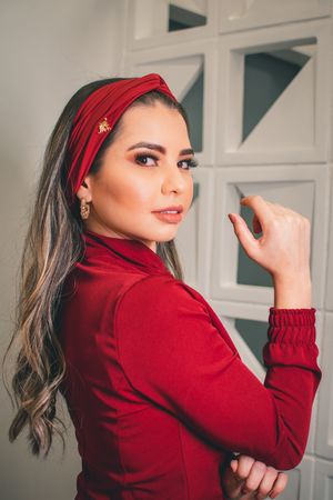Professional portrait in red outfit with red headband against geometric wall background.