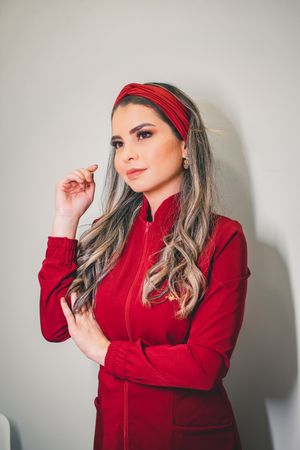 Fashion portrait of person in red zip-up jacket and headband against neutral background.