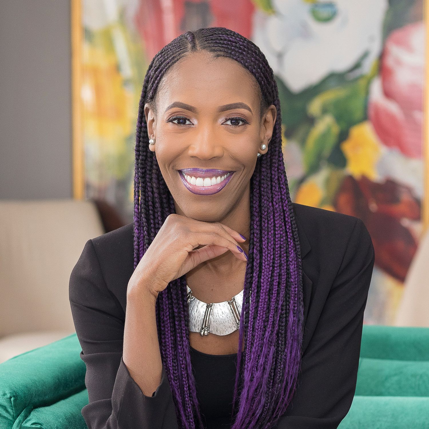 Colorful portrait of a black woman with braids in a business professional suit sitting on a couch in Detroit home.