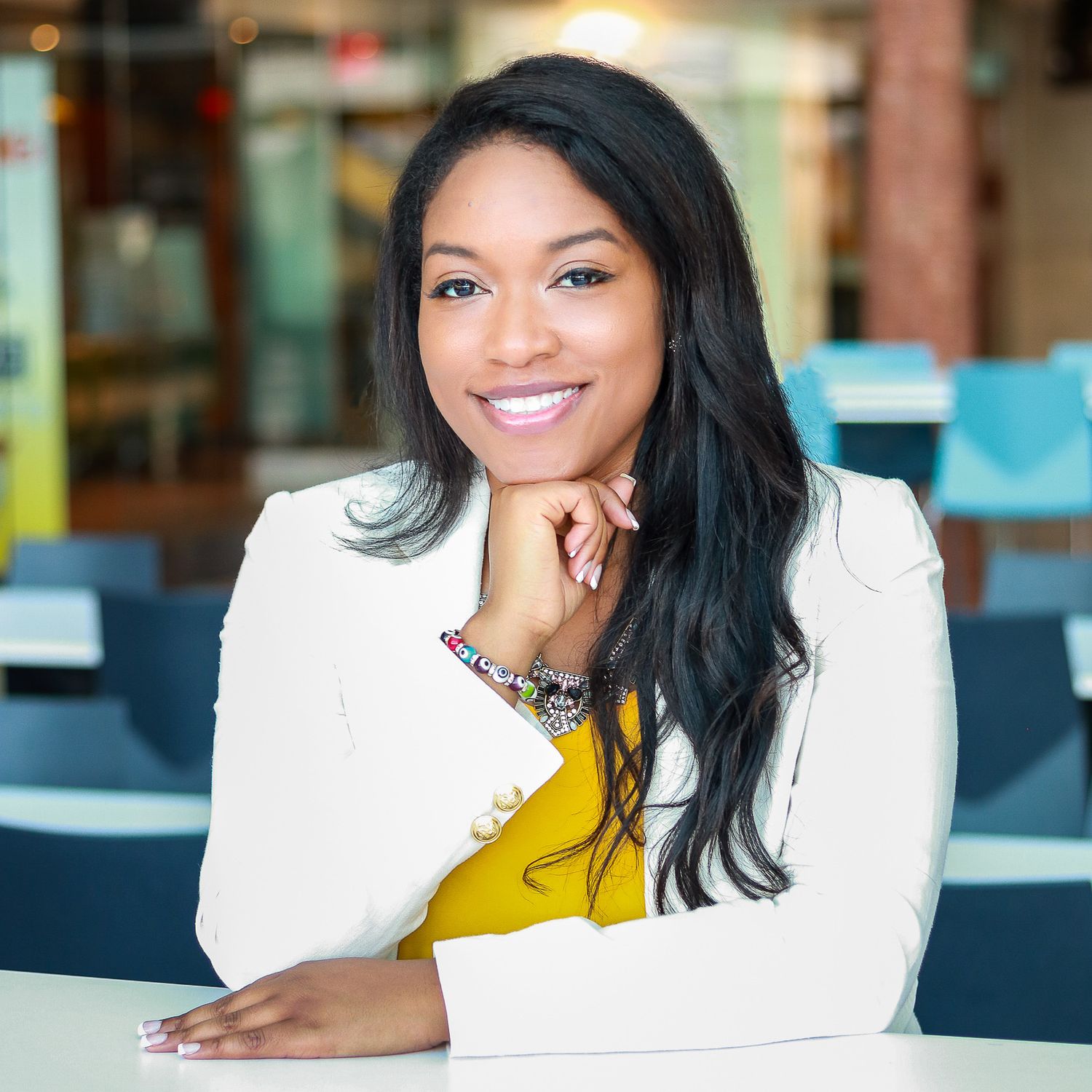 Portrait of a black woman in business professional attire sitting at a table inside Detroit's Renaissance Center.