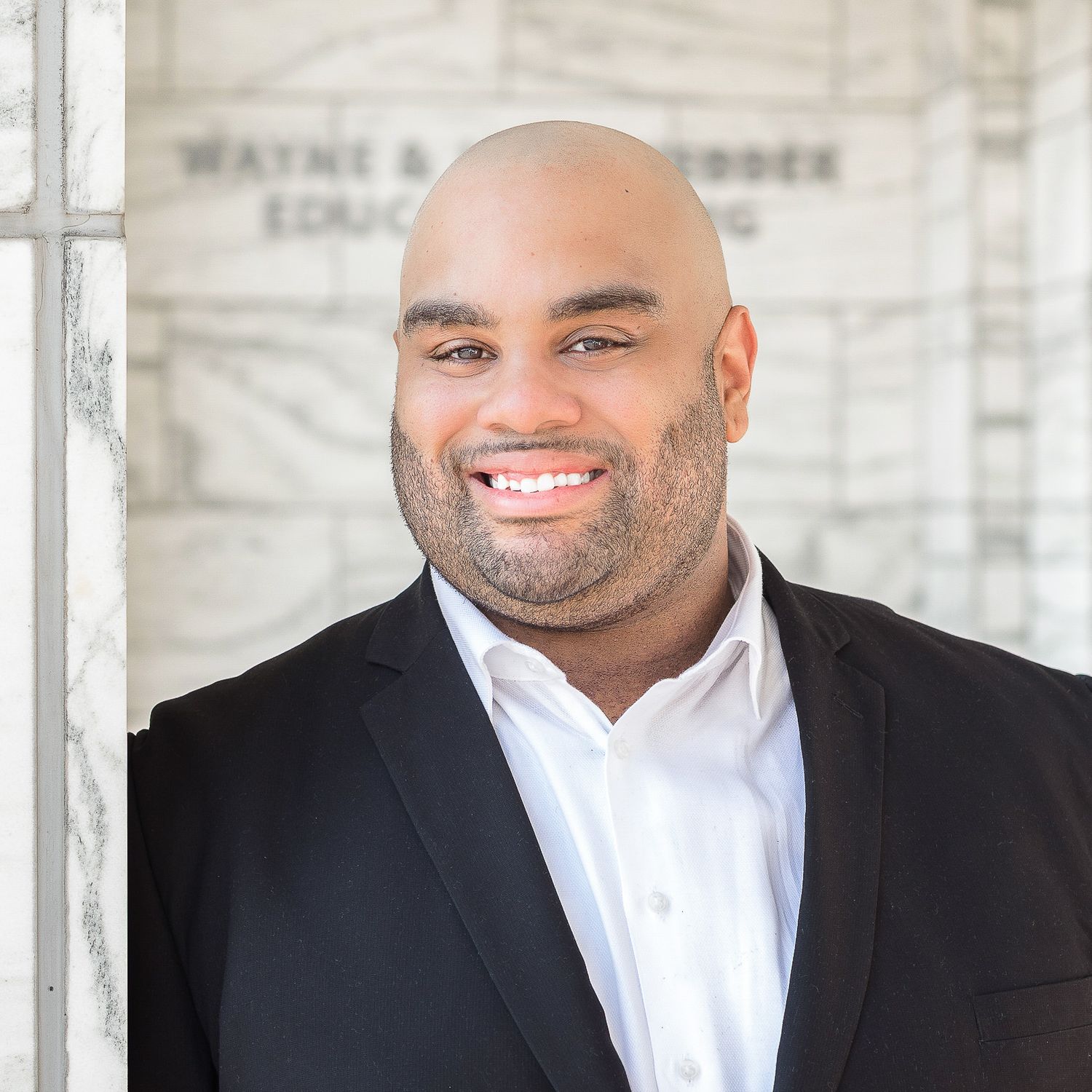 Portrait of a black man in a business professional suit outside of the Detroit Institute of Arts.