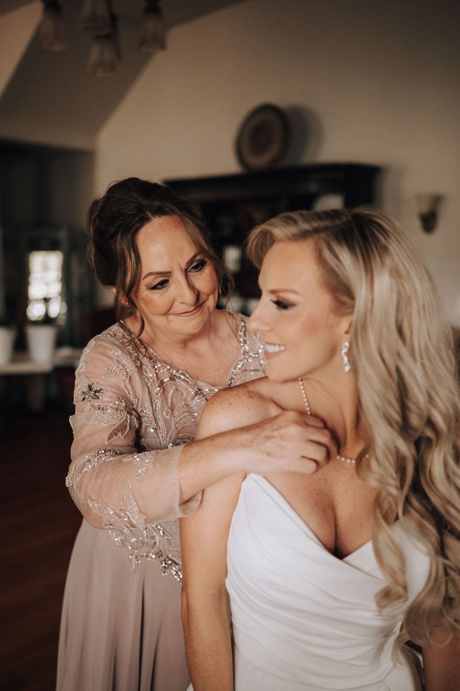 Intimate getting ready moment with bride in white strapless gown.