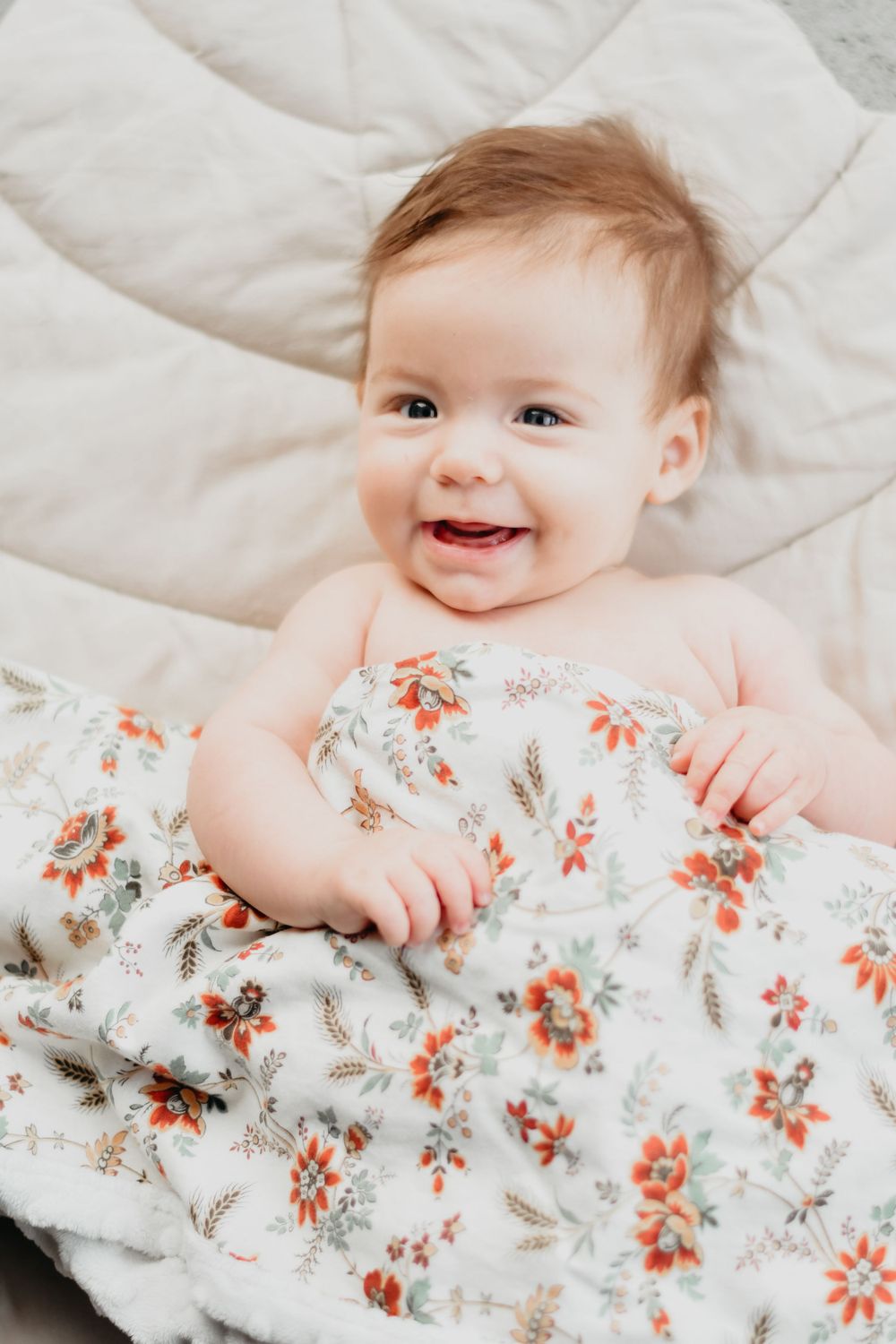 A joyful moment on white bedding with a floral print blanket.