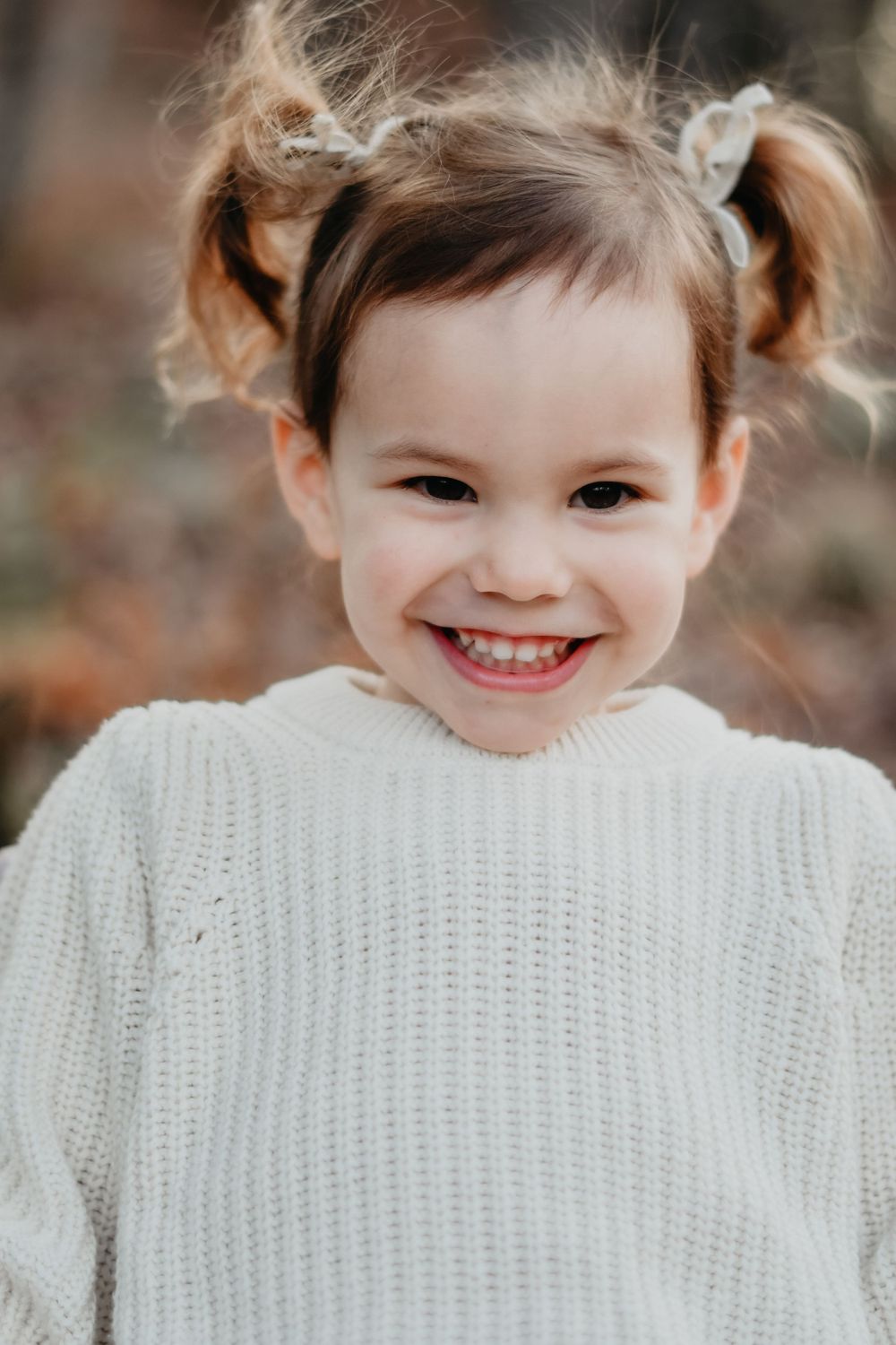 A bright smile and cozy white sweater on a crisp autumn day.
