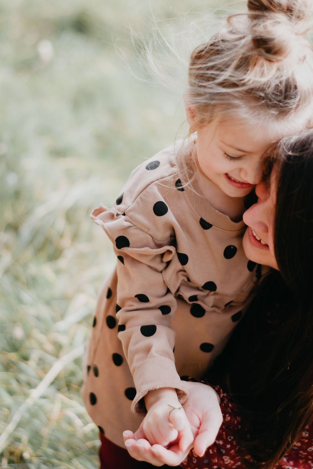 An intimate moment shared outdoors wearing a polka dot dress on a sunny day.