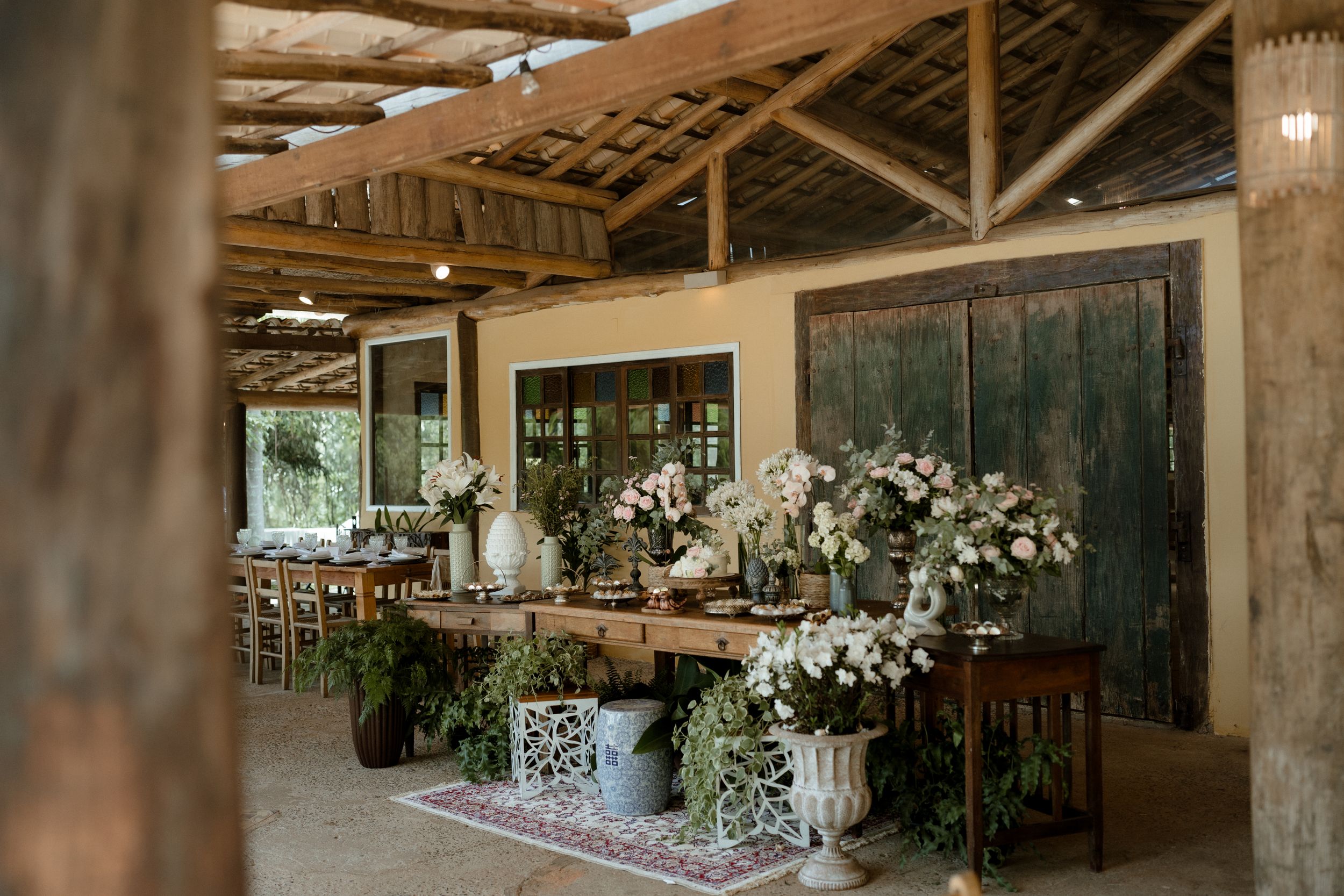 Rustic wedding venue with wooden beams and white floral arrangements.