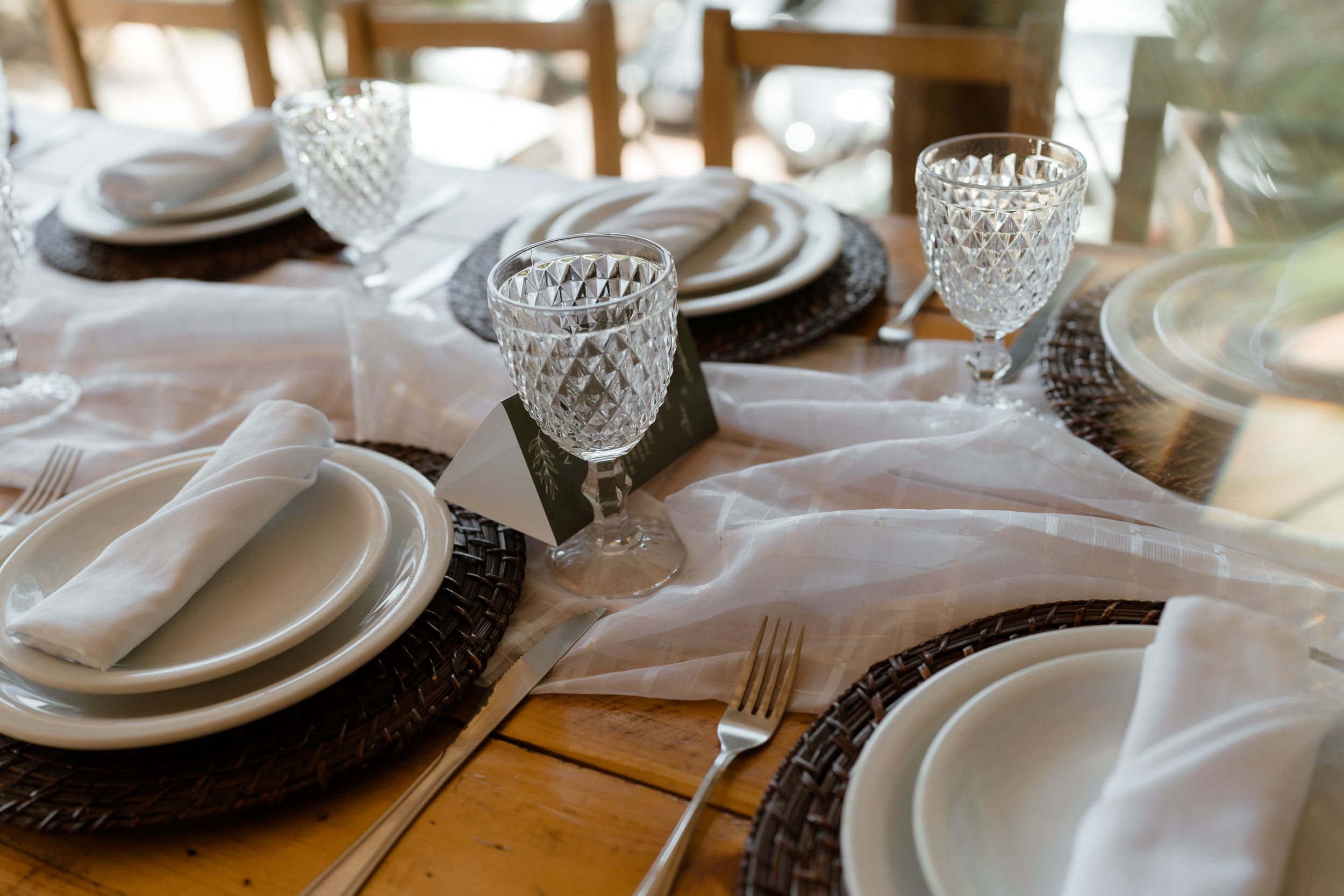 Elegant table setting with crystal glassware and white linens in natural lighting.