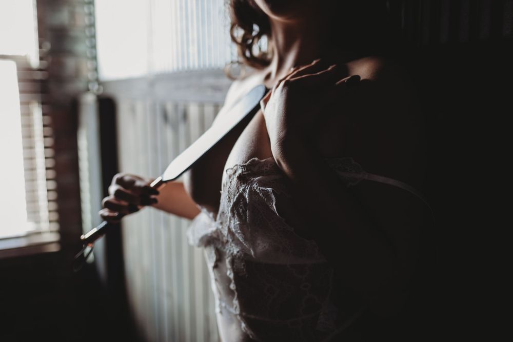 Silhouette against window light creates moody atmosphere in intimate portrait.