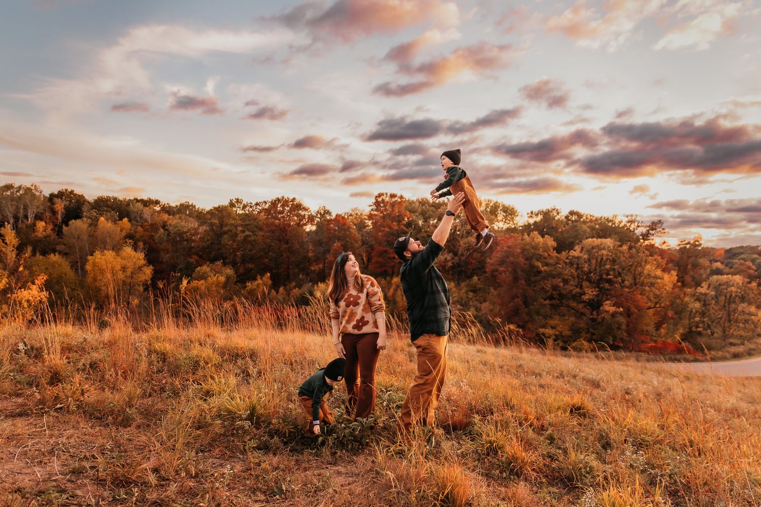 A family plays together in a field during golden hour at their family photography session in Chaska, MN.