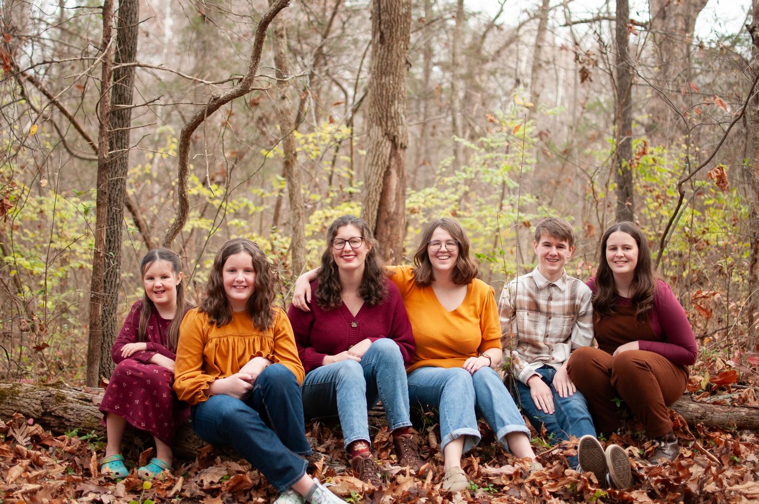 Children sitting on a log outside photos