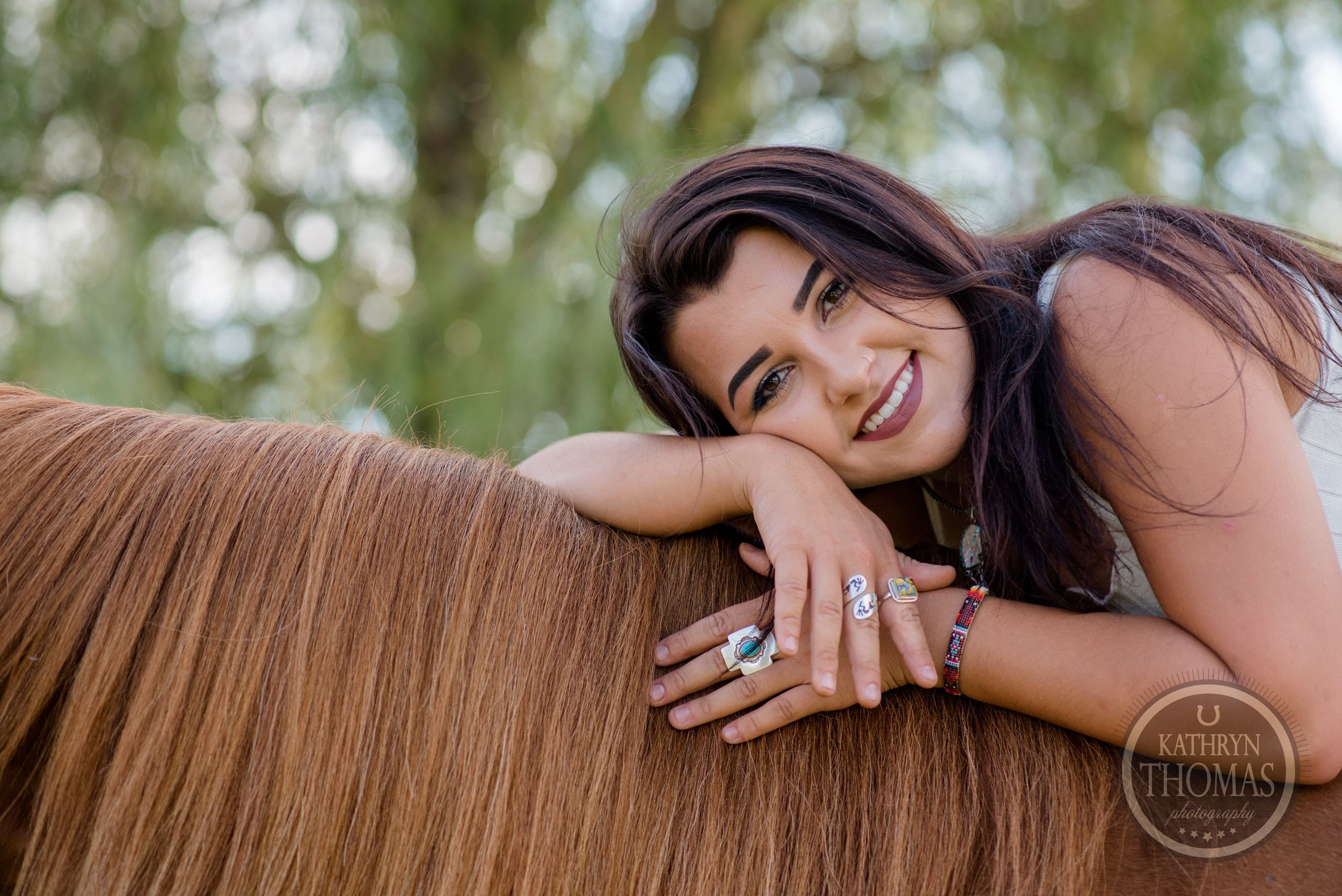 Person resting on brown horse's back in outdoor setting with natural lighting.