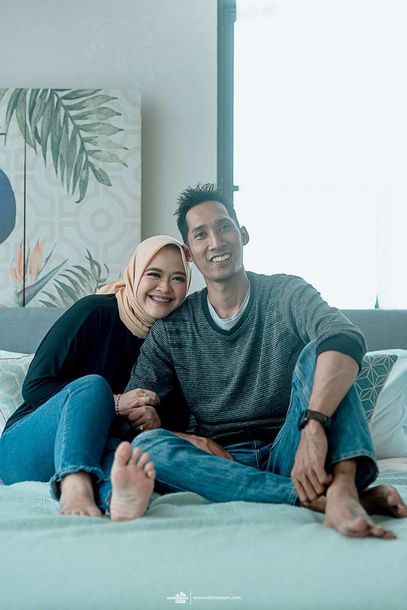 Relaxed couple in casual wear sharing intimate moment on light blue couch.