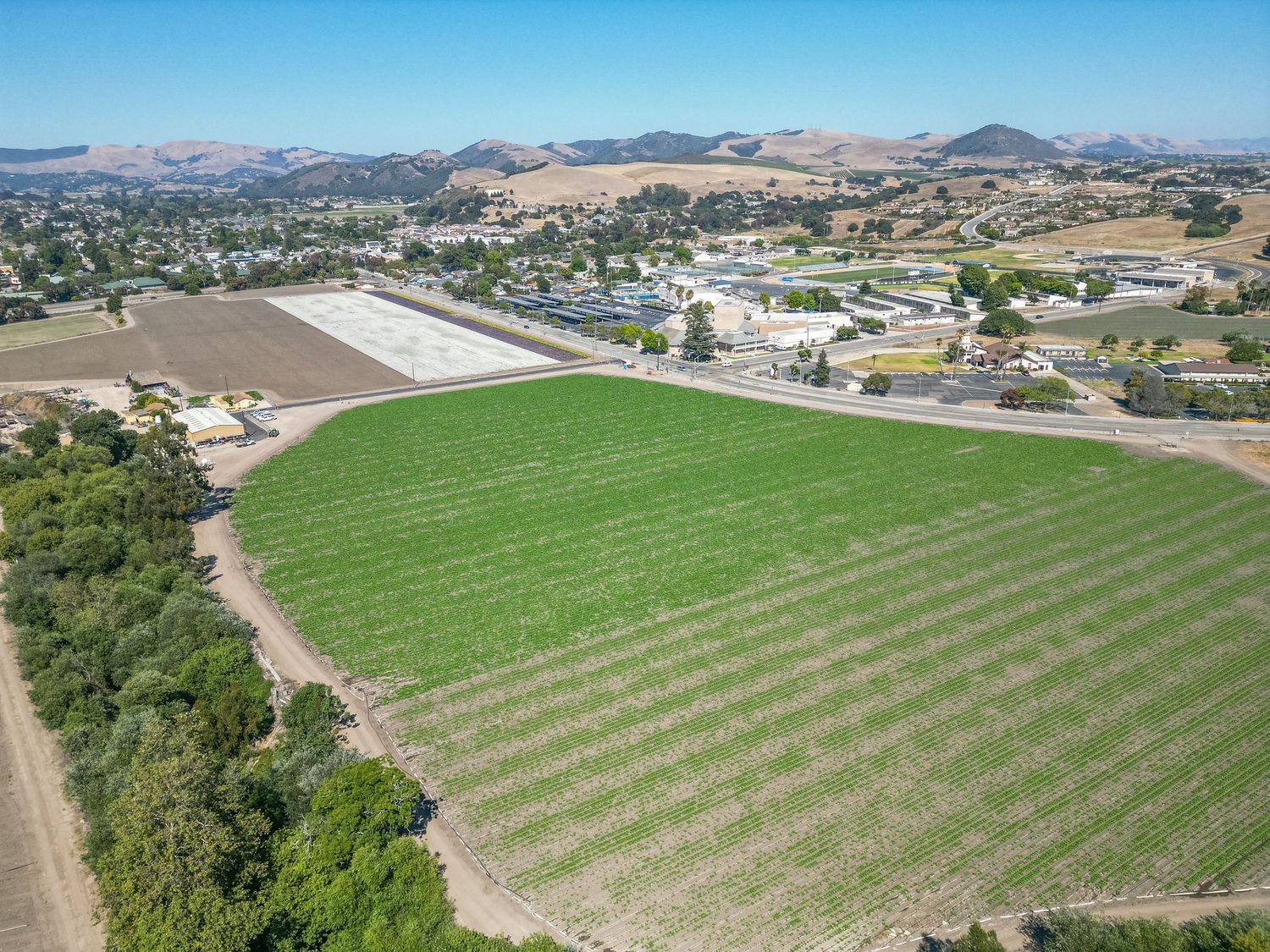 Aerial view of green agricultural fields surrounded by rolling hills and rural development.