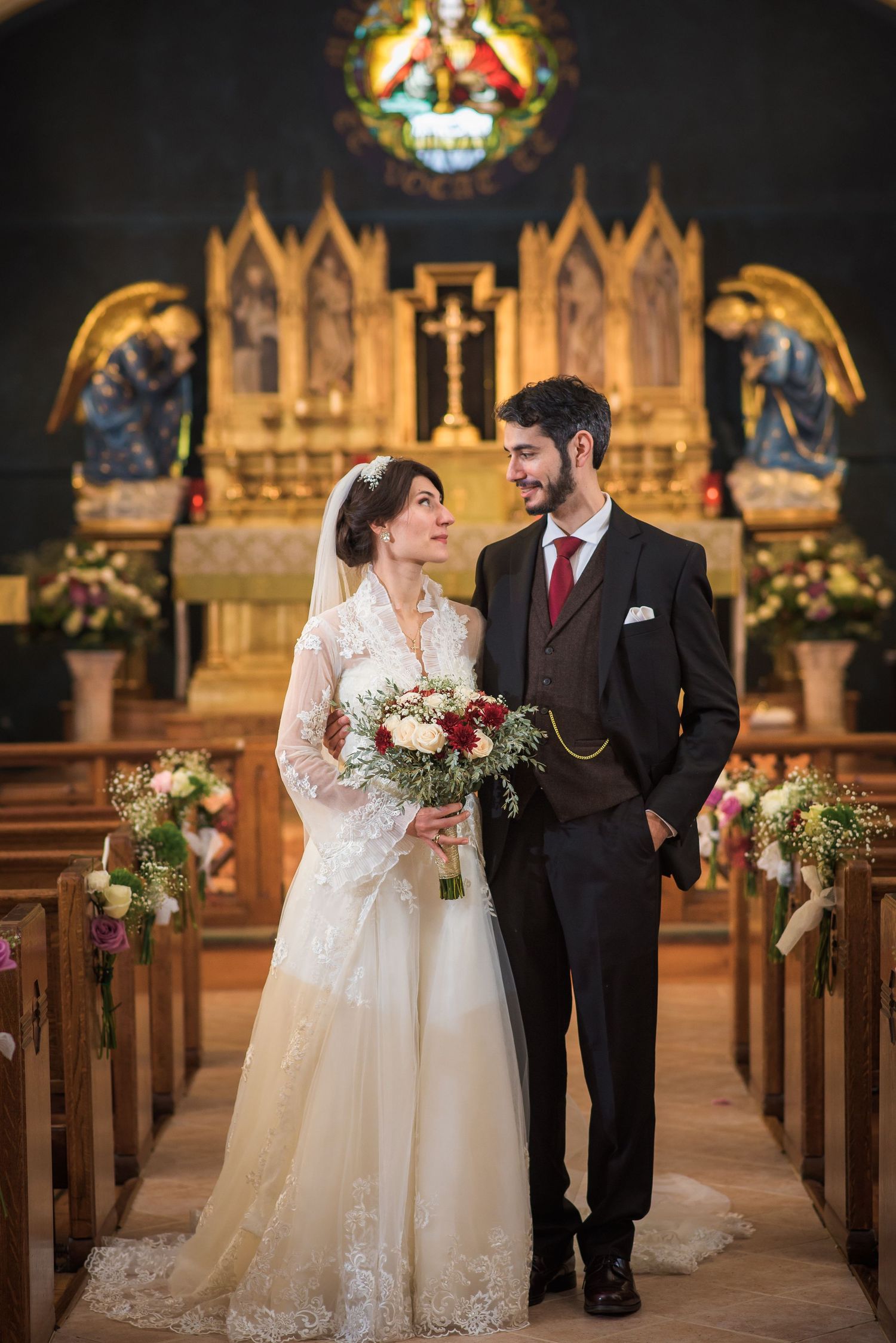 Newlyweds share a loving glance in a stunning ornate church aisle after their ceremony.