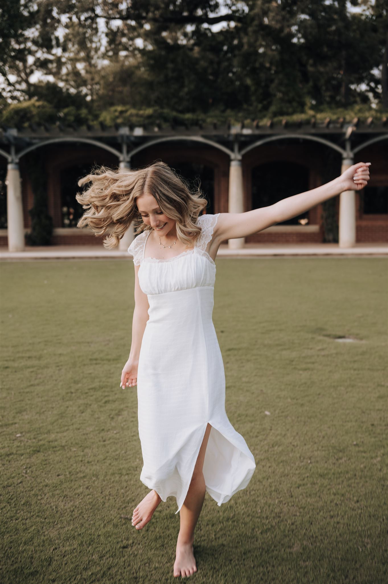 Carefree spinning movement captured in flowing white dress against columned architecture.