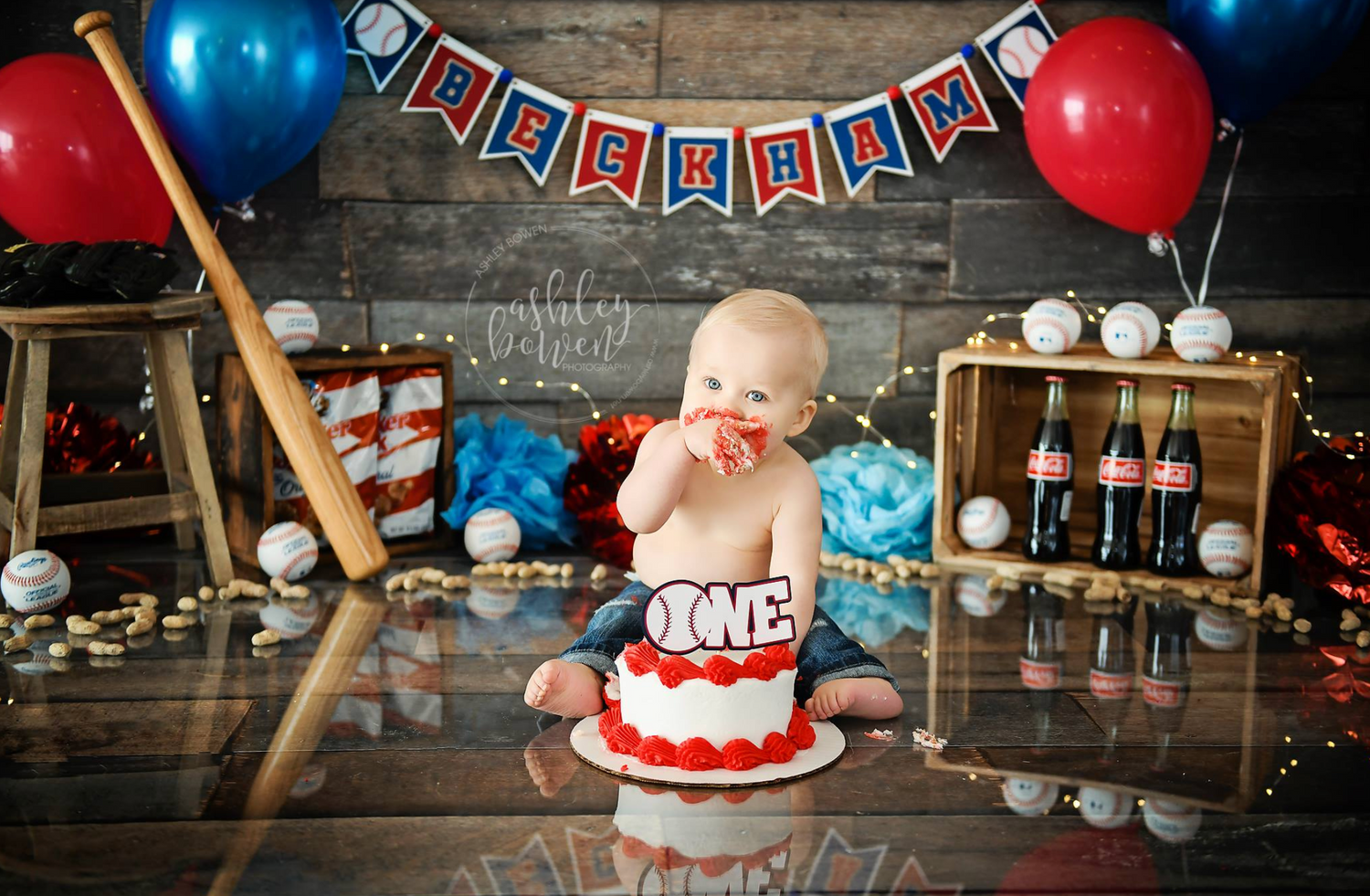 Baby boy baseball themed first birthday cake smash with red and blue decor.