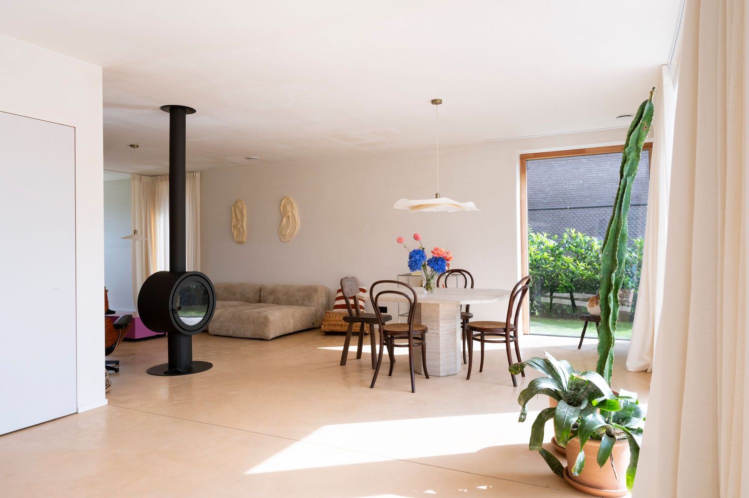 Minimalist white interior with natural lighting and houseplants creating a bright, airy living space.