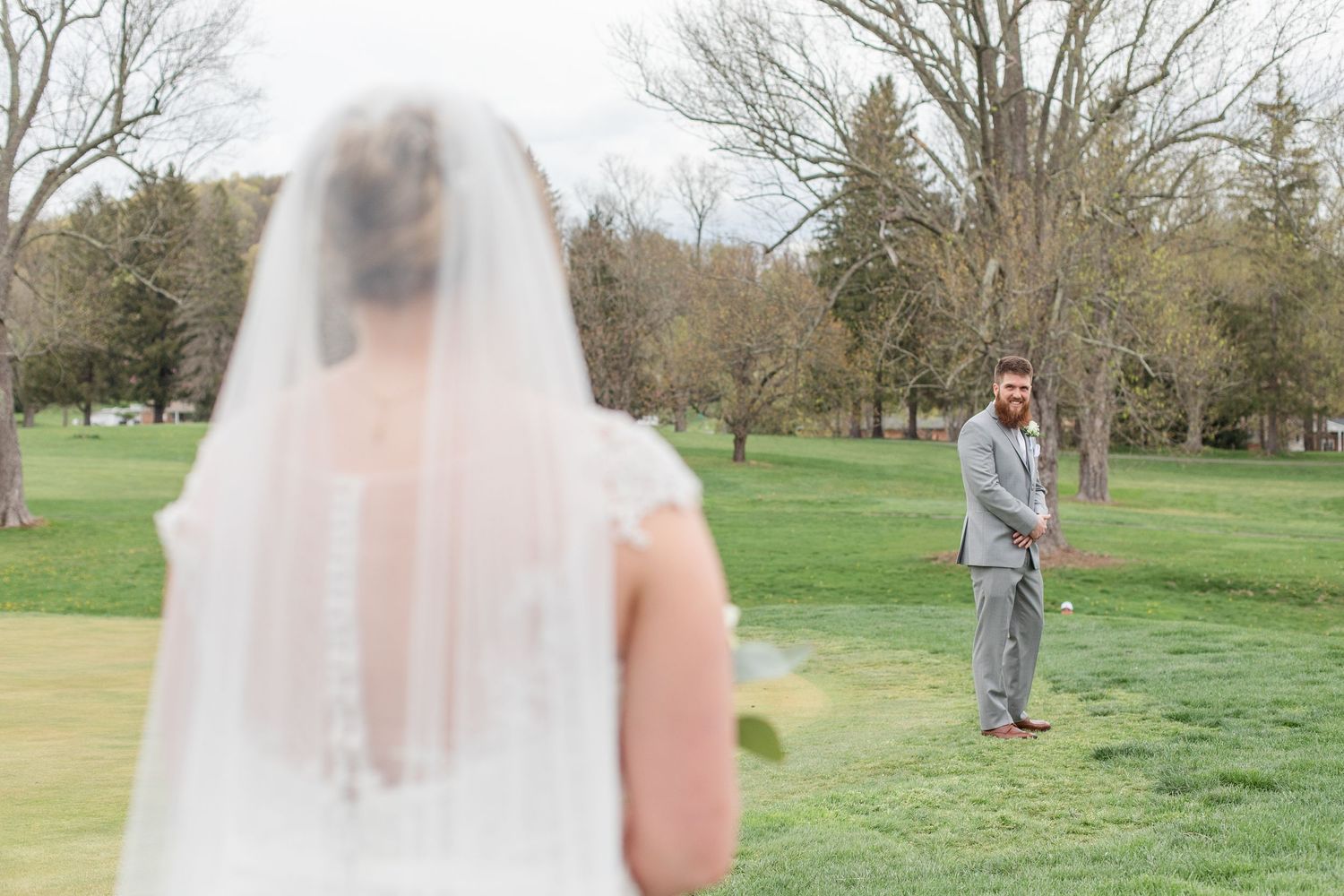 Couple's first look captured from behind in a serene outdoor park setting.