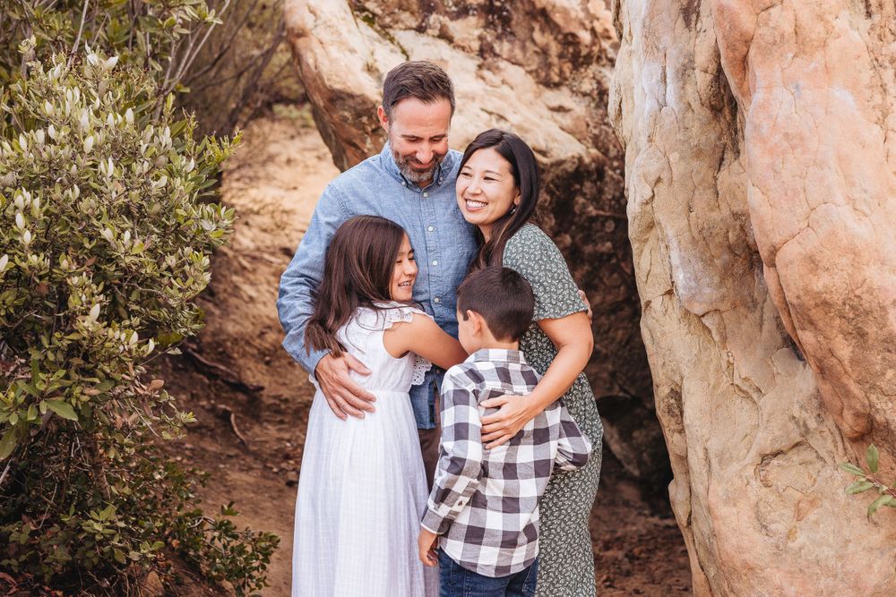 A family sharing an intimate embrace against a rocky desert backdrop.