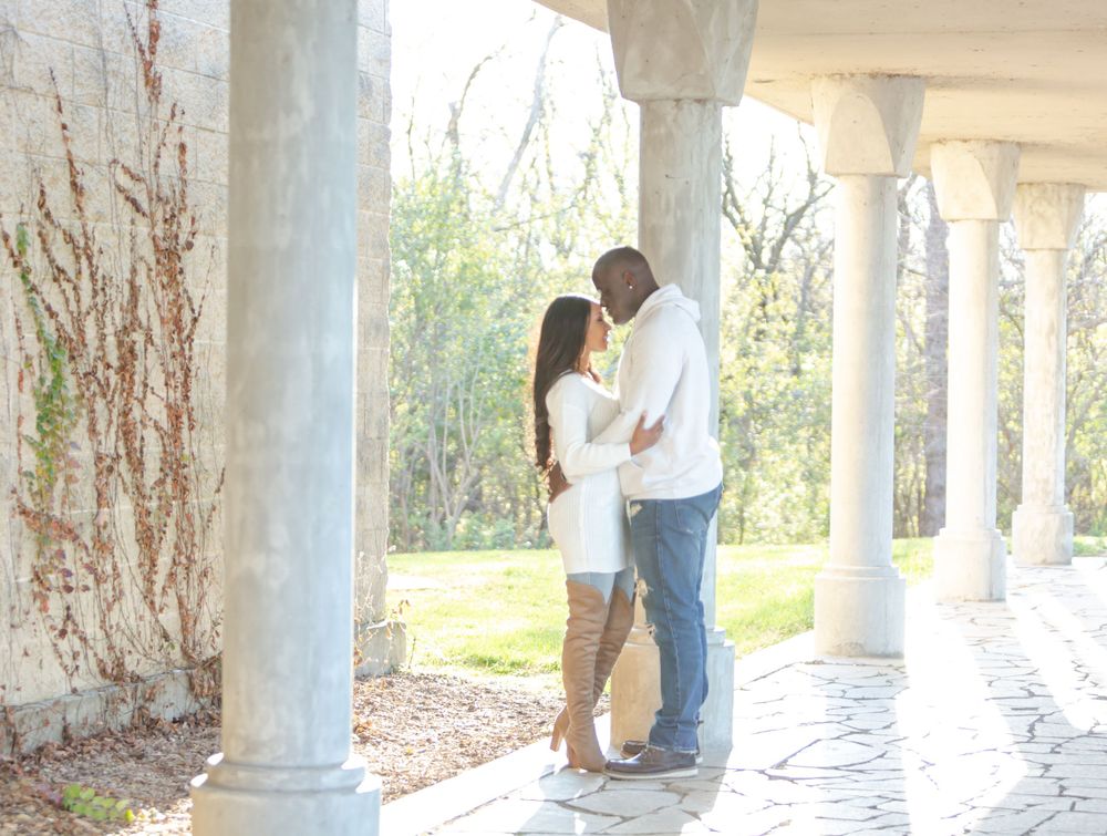 Couple sharing an intimate moment under white columns during golden hour.