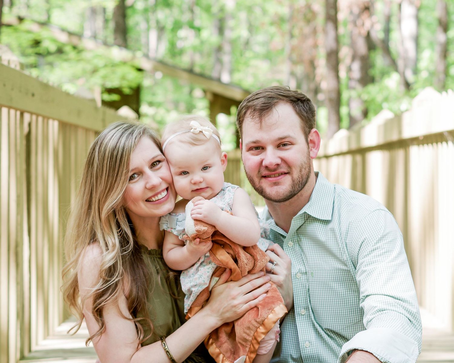 family of three hugging on a bridge