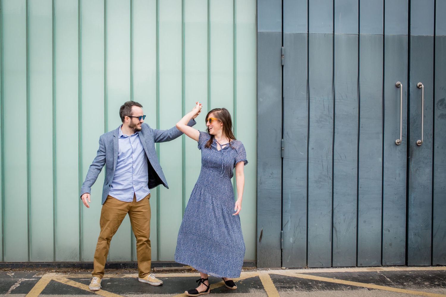 couple dancing together in front of a garage wall
