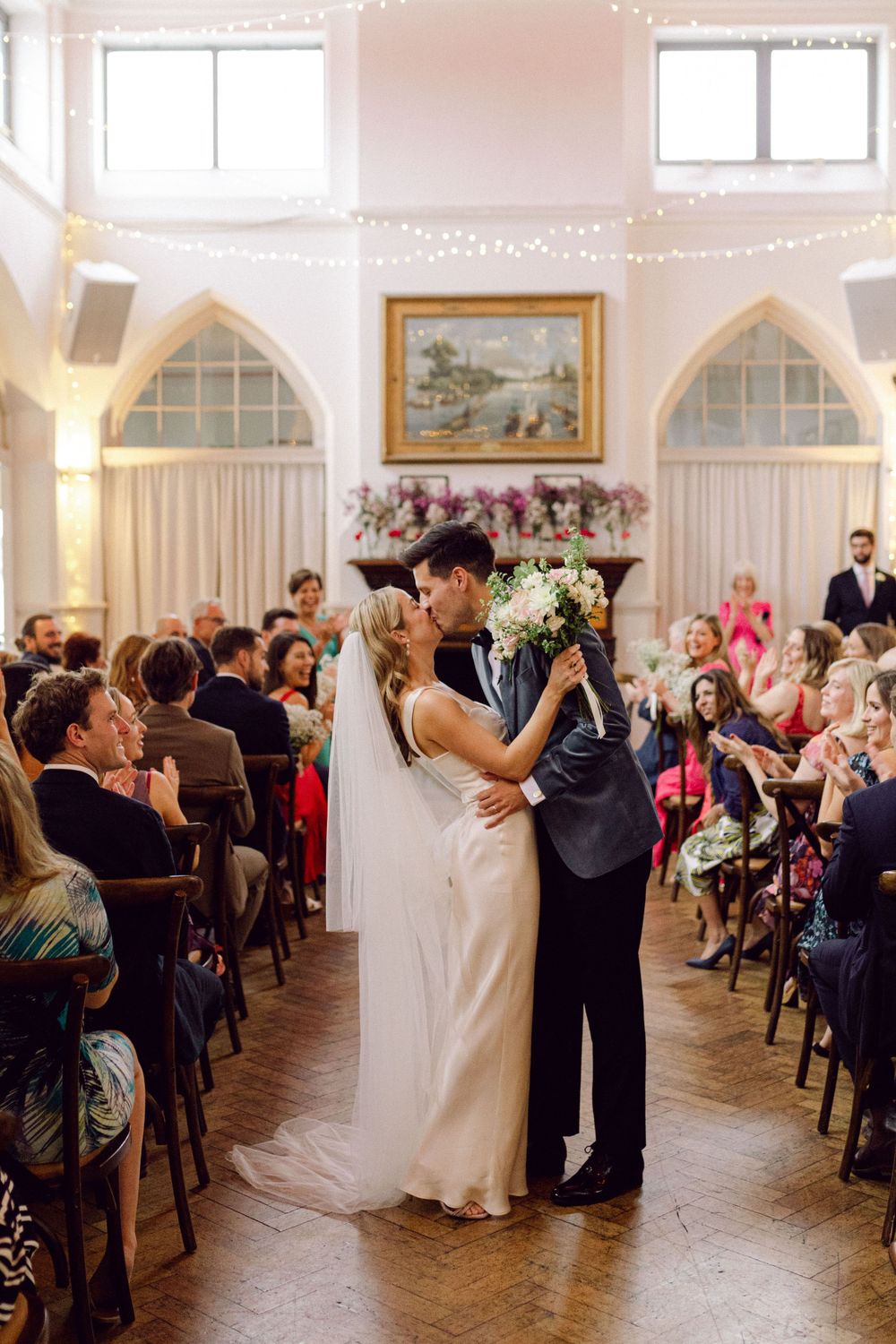 Bride and groom kiss halfway down the aisle after their Thames Rowing Club London wedding ceremony